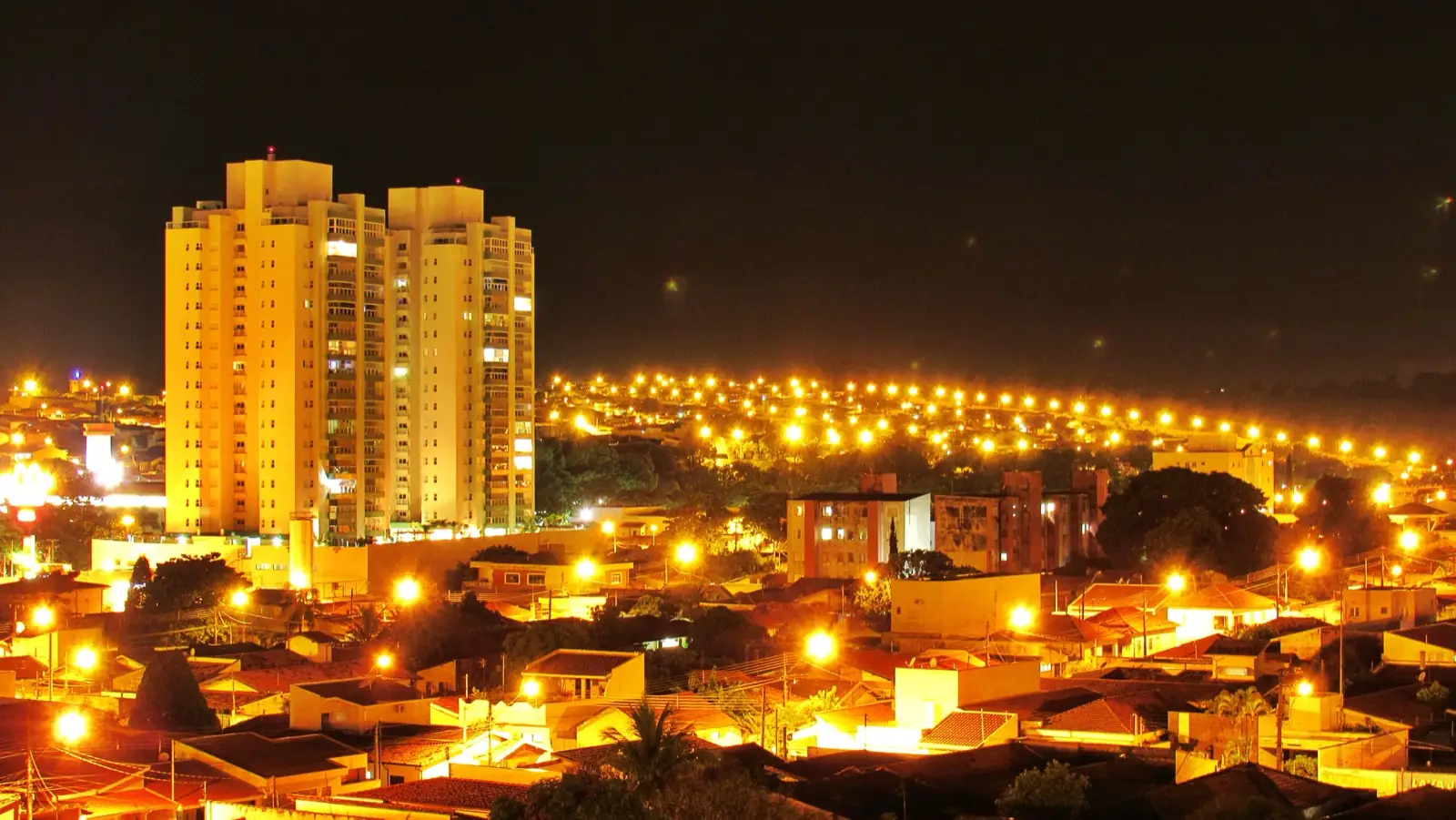 Centro de Araras SP iluminado à noite, com movimento de pessoas nas ruas